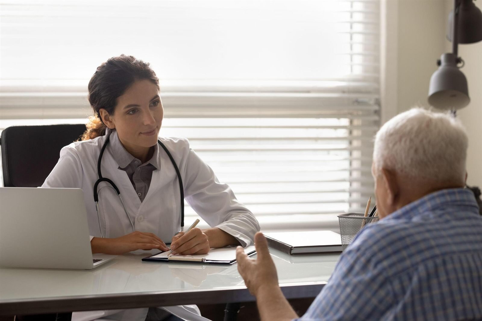 A GP listening carefully to an older patient during a consultation at the clinic