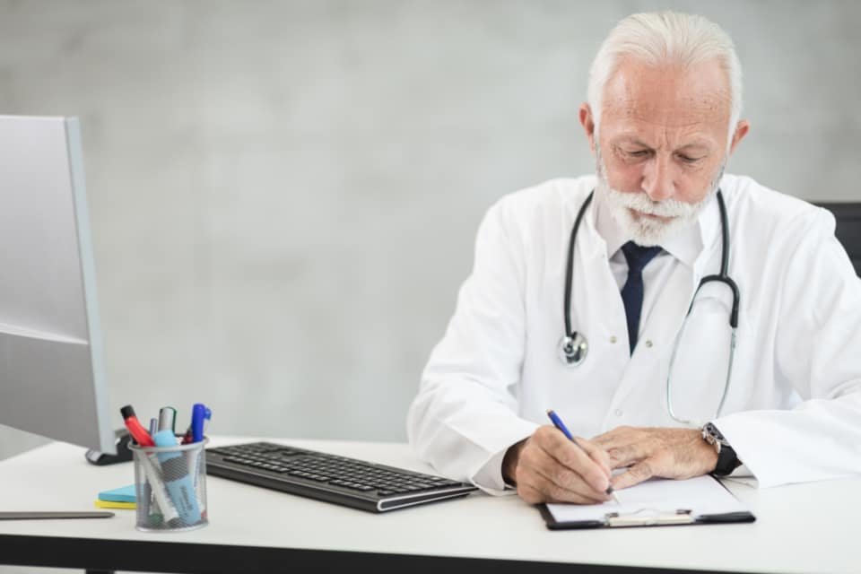 A GP reviewing patient notes at a desk
