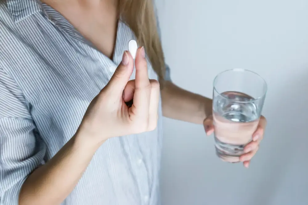 Person taking medication with water, representing migraine treatment